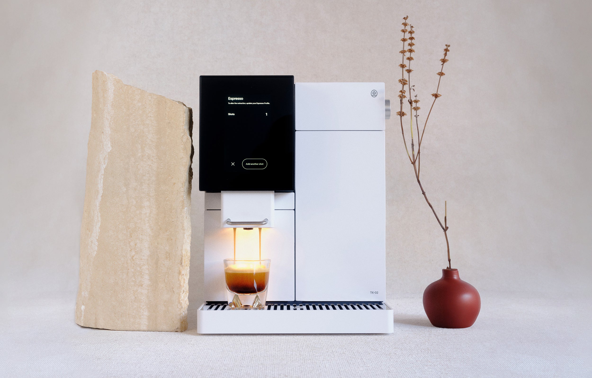 White TK-02 pouring an espresso shot on a linen table next to a slab of marble and a vase